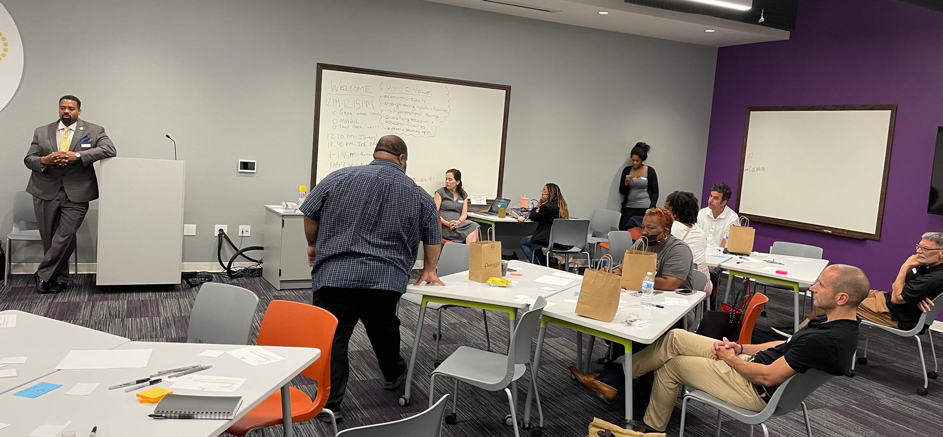The Forbes Funds team conducts a human-centered design workshop with local Pittsburgh nonprofit MYDC, showing participants and Fred Brown and Olivia Benson next to a podium and large whiteboard